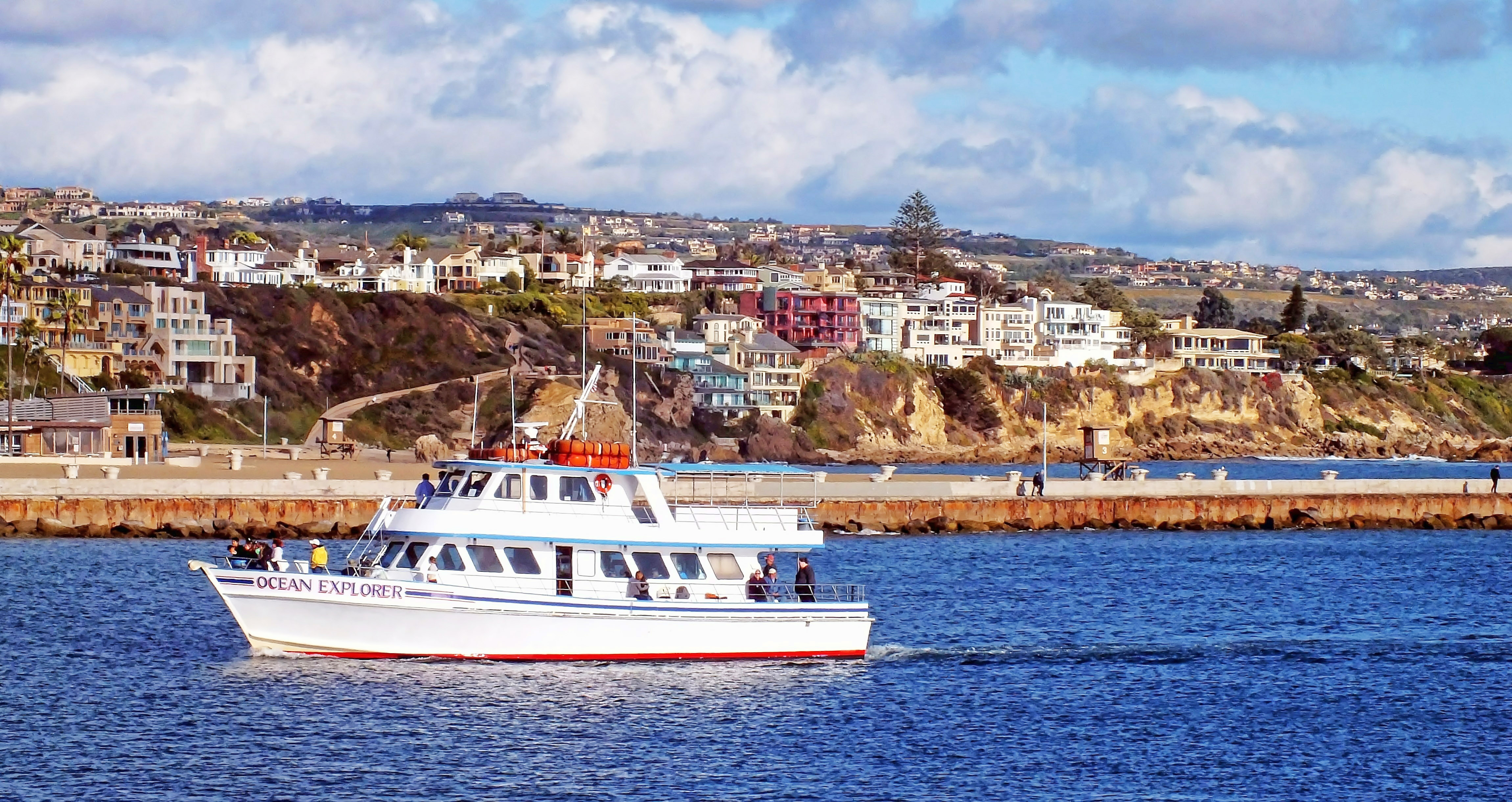 Whale watchers on a boat take a tour in Southern California, traveling along the coast of Newport Beach.